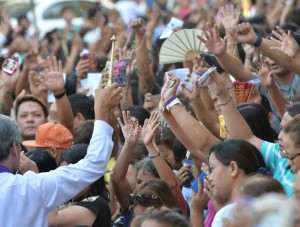  A worker is touching religious items of followers of Roman Catholic during a  ceremony in a Church in Manila, Philippines.