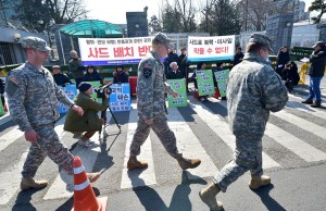  American soldiers passing in front of protesters of a rally staged against the talks about installation of high altitude defence system in Seoul.