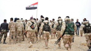 Syrian soldiers gather around the national flag in Palmyra on Sunday.