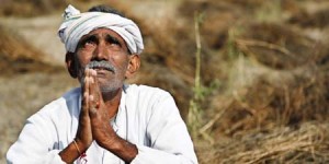 An Indian farmer looks skyward as he sits in his field with wheat crop that was damaged in unseasonal rains and hailstorm at Darbeeji village, in the western Indian state of Rajasthan, Friday, March 20, 2015. Recent rainfall over large parts of northwest and central India has caused widespread damage to standing crops. (AP Photo/Deepak Sharma)