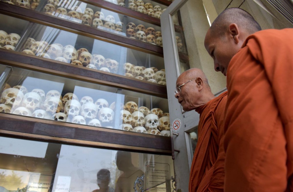 Cambodian monks watching skulls kept in a killing fields memorial in  Phnom Penh, Cambodia.