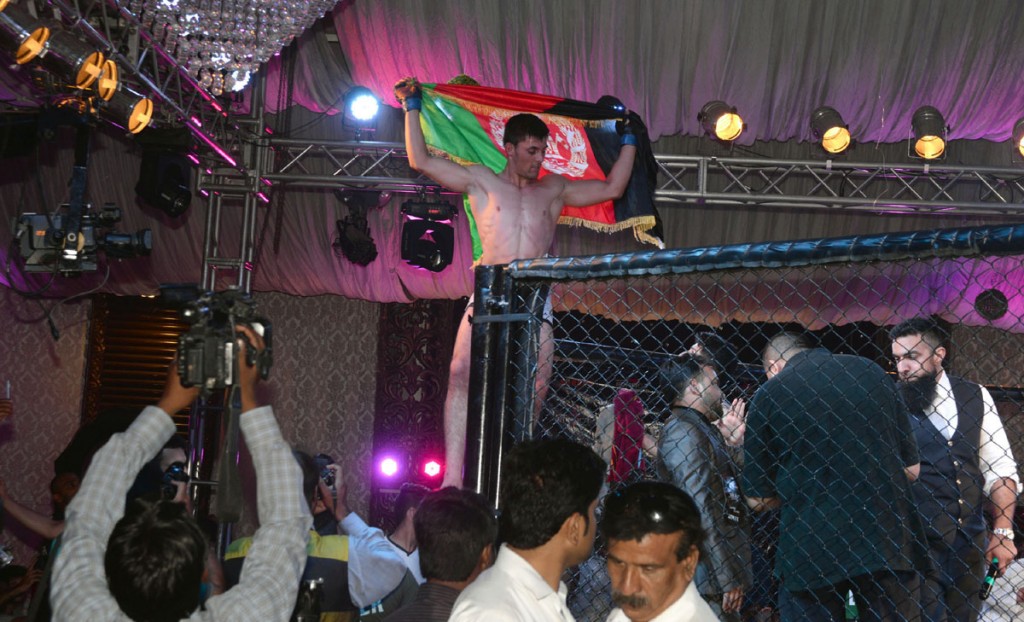An Afghan wrestler flies his national flag after winning a contest during International Mix Martial Arts Wrestling Championship in Lahore on Sunday.-DNA 