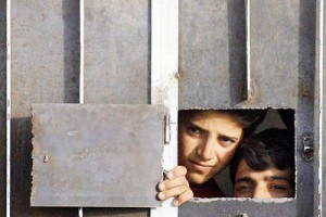 Afghan refugees peer through the window of their cell as they are detained in the Iranian city of Zahedan after illegally crossing into Iran 10 October 2001. Iran, already host to more than two million Afghan refugees, is pleading economic constraint as a reason for closing its frontiers to those fleeing US airsttrikes. AFP PHOTO / BEHROUZ MEHRI / AFP PHOTO / BEHROUZ MEHRI