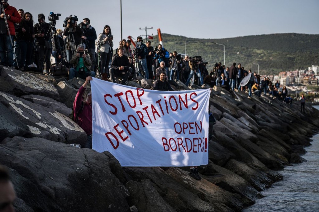 German activists are displaying an anti-banner on the arrival of a Turkish ship carrying  immigrants sent back from Greece in Dikili, Turkey.-AFP