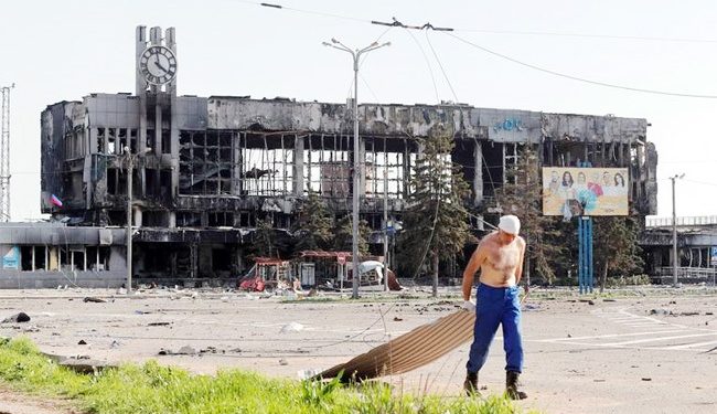 A man drags metal board near a railway station building destroyed in the southern port city of Mariupol, Ukraine