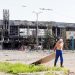 A man drags metal board near a railway station building destroyed in the southern port city of Mariupol, Ukraine