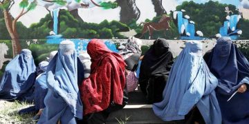 Afghan women wait to receive a food package