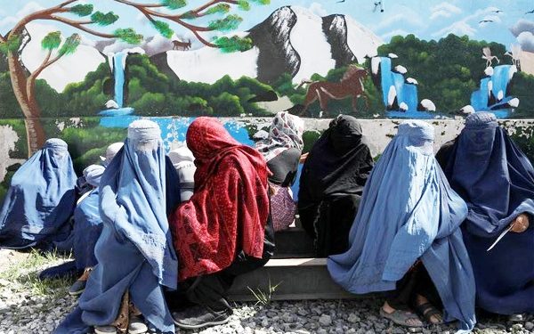 Afghan women wait to receive a food package
