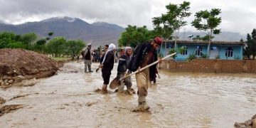People work outside of damaged houses after a heavy rain in Baghlan province, Afghanistan