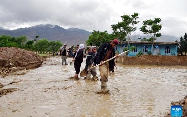 People work outside of damaged houses after a heavy rain in Baghlan province, Afghanistan