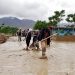 People work outside of damaged houses after a heavy rain in Baghlan province, Afghanistan